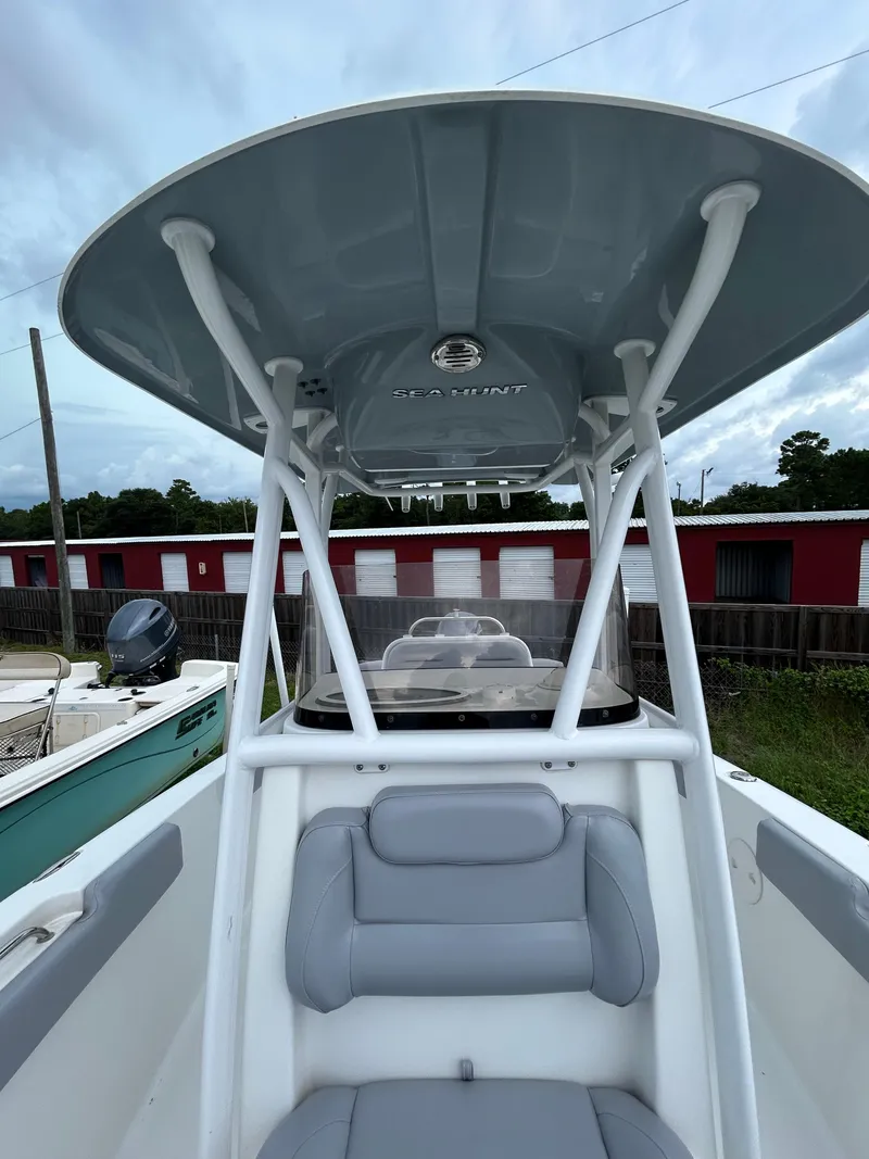 Slide: The Image of 2019 Sea Hunt 225 Ultra boat with T-top and seating, parked outdoors. - 11