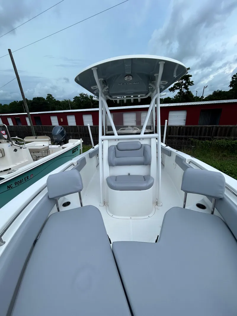 Slide: The Image of 2019 Sea Hunt 225 Ultra boat with gray seating and T-top, docked outdoors. - 12
