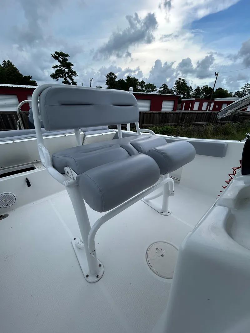 Slide: The Image of 2019 Sea Hunt 225 Ultra boat with gray cushioned seating, under a cloudy sky. - 20