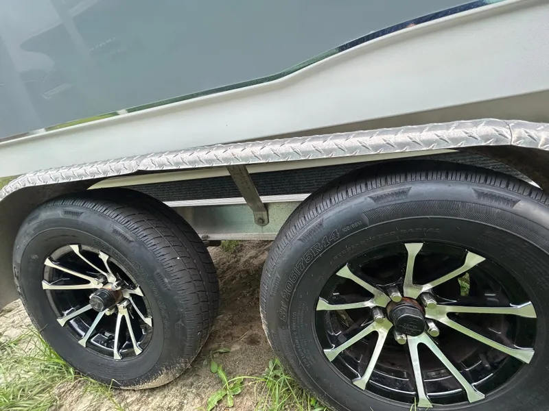 Slide: The Image of Trailer wheels of a 2019 Sea Hunt 225 Ultra boat on grass. - 29
