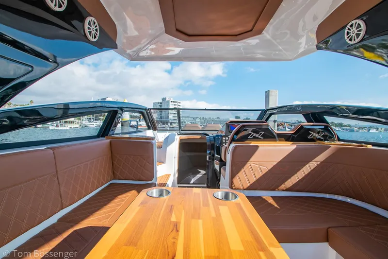 Slide: The Image of 2023 NX Boats 340 Sport Coupe interior with luxurious seating and wooden table, overlooking marina. - 11