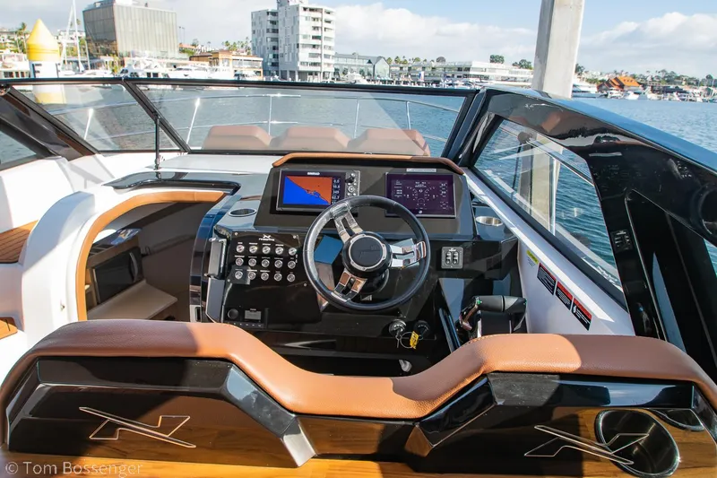 Slide: The Image of 2023 NX Boats 340 Sport Coupe cockpit with modern controls and waterfront view. - 13