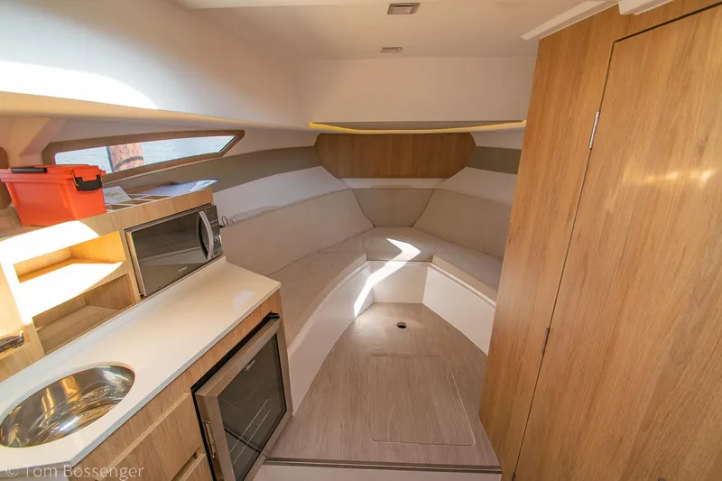 Slide: The Image of Interior of 2023 NX Boats 340 Sport Coupe, featuring kitchenette and cozy seating area. - 19