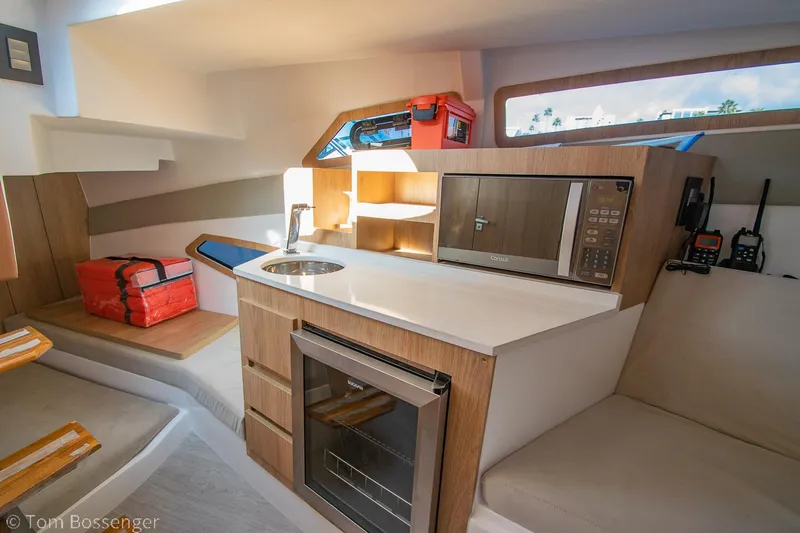 Slide: The Image of Interior of 2023 NX Boats 340 Sport Coupe featuring kitchenette with sink, microwave, and seating. - 22