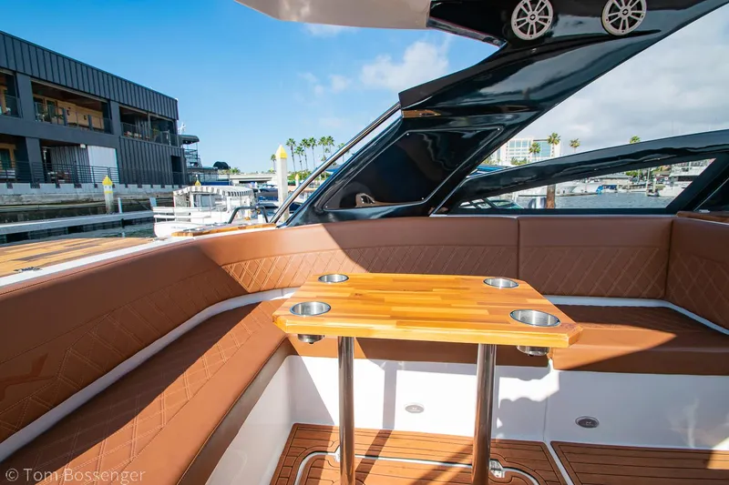 Slide: The Image of 2023 NX Boats 340 Sport Coupe interior with wooden table and leather seating. - 9