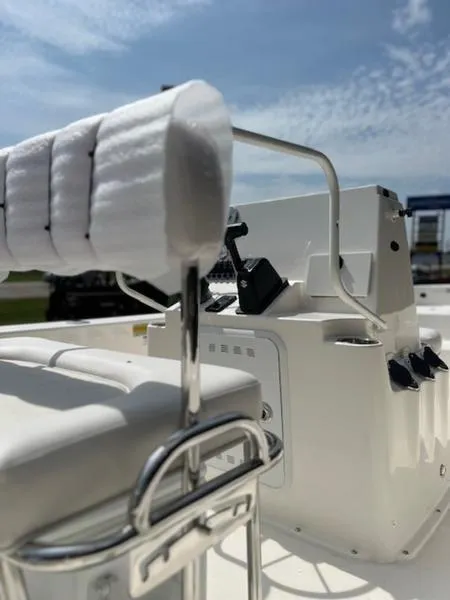 Slide: The Image of 2024 Sundance DX22 HPX boat interior with white cushioned seating and control panel. - 2