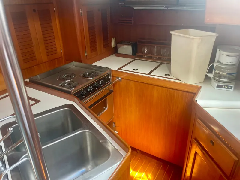 Slide: The Image of 1983 Bristol 45.5 Center Cockpit yacht kitchen with stove, sink, and wooden cabinetry. - 19