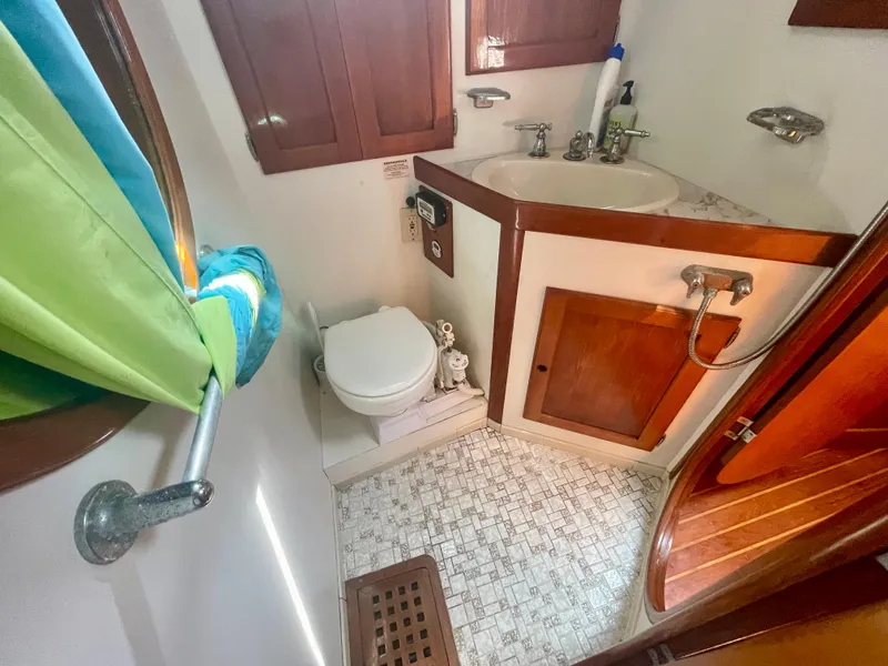 Slide: The Image of 1983 Bristol 45.5 Center Cockpit bathroom with sink, toilet, and wooden cabinets. - 24
