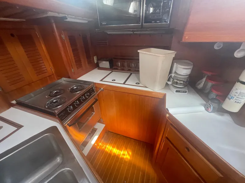 Slide: The Image of 1983 Bristol 45.5 Center Cockpit yacht kitchen with stove, sink, and wooden cabinetry. - 27