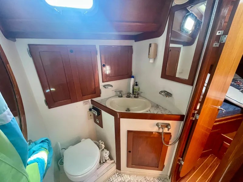 Slide: The Image of 1983 Bristol 45.5 Center Cockpit bathroom with sink, toilet, and wooden cabinets. - 29