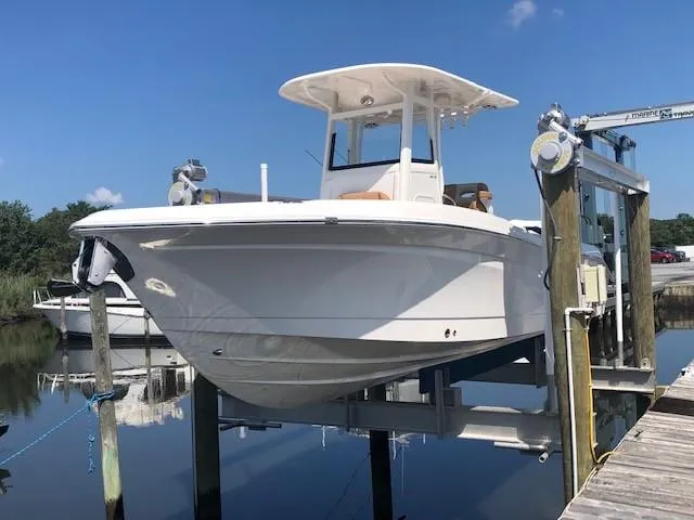 The Image of 2023 NauticStar 24 XS boat docked on a lift under a clear blue sky. - 0