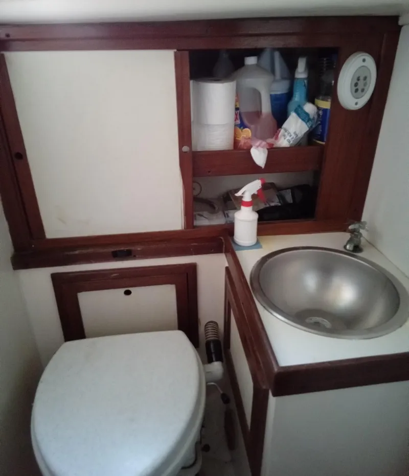Slide: The Image of 1971 Tartan 34C boat bathroom with sink, toilet, and storage shelves. - 10