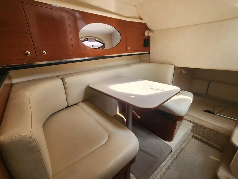 Slide: The Image of 2004 Sea Ray 290 Amberjack cabin interior with beige seating and wooden cabinets. - 18
