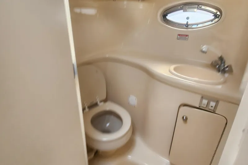 Slide: The Image of 2004 Sea Ray 290 Amberjack bathroom with toilet, sink, and porthole window. - 36