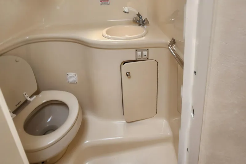 Slide: The Image of 2004 Sea Ray 290 Amberjack boat bathroom with toilet, sink, and storage cabinet. - 38