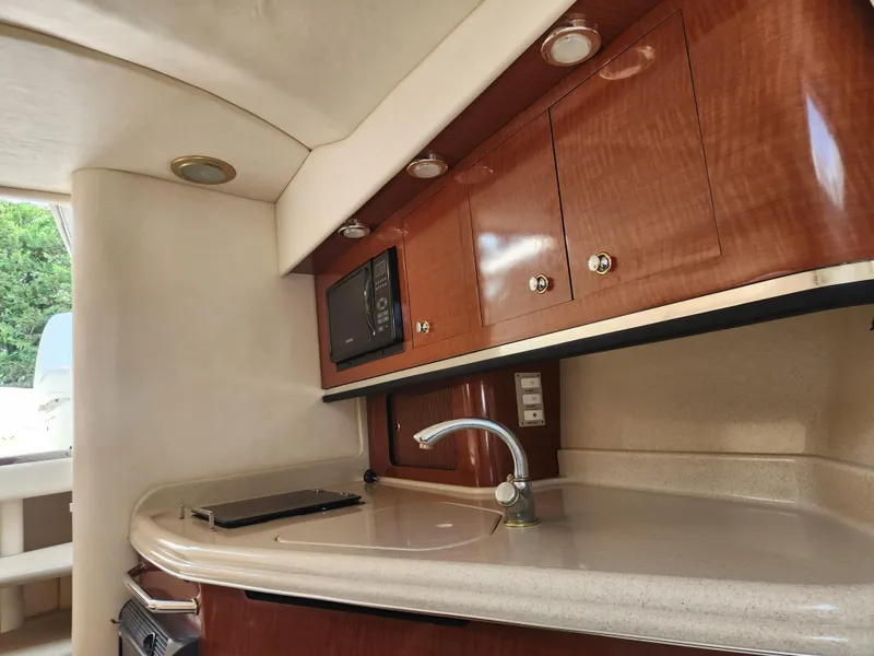 Slide: The Image of 2004 Sea Ray 290 Amberjack boat interior kitchen with wooden cabinets and countertop. - 5