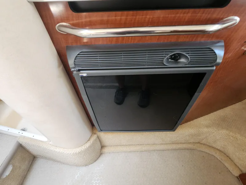 Slide: The Image of 2004 Sea Ray 290 Amberjack cabin refrigerator with wooden paneling and carpeted flooring. - 6
