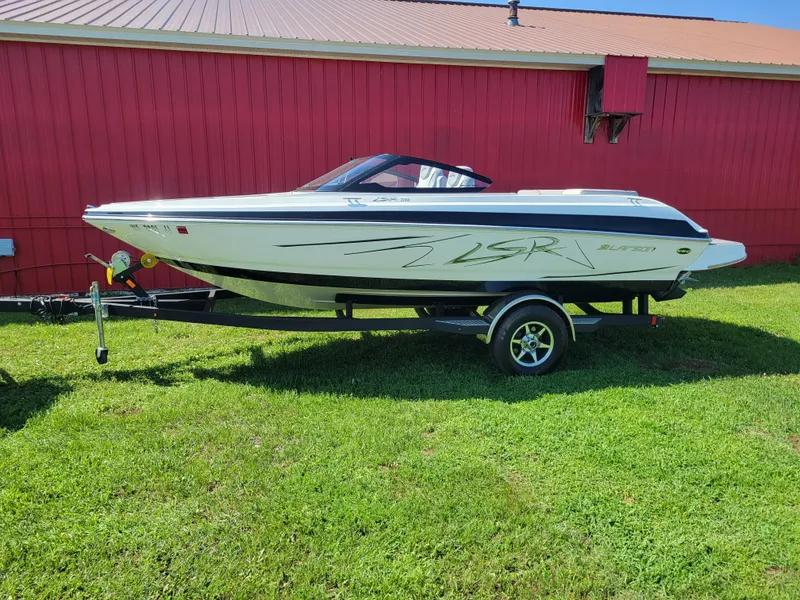 The Image of 2014 Larson LSR 2100 I/O boat on trailer, parked on grass near a red barn. - 1
