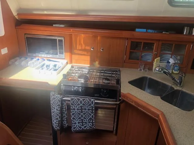 Slide: The Image of 2008 Hunter 41 Deck Salon kitchen with microwave, stove, and double sink. - 12