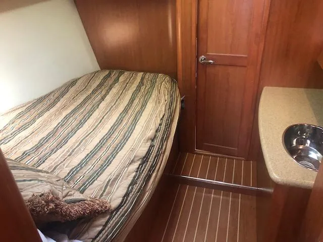 Slide: The Image of 2008 Hunter 41 Deck Salon bedroom with bed, wooden door, and small sink. - 14