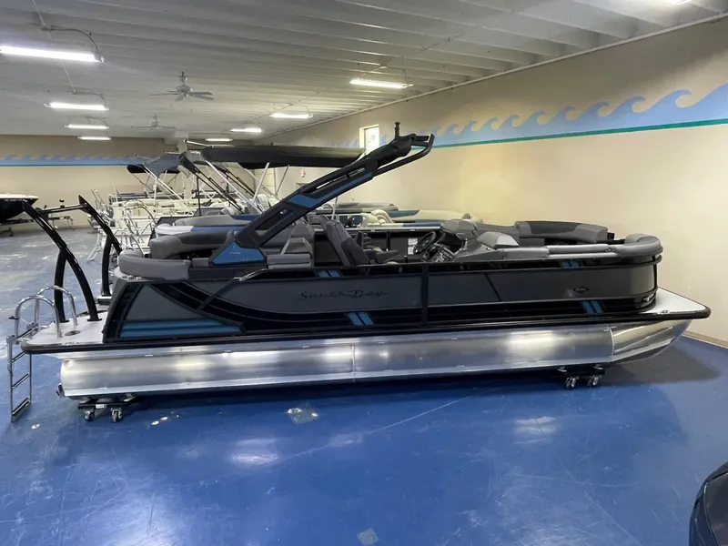 Slide: The Image of 2026 South Bay 525 RS 3.0 Arch pontoon boat in showroom, side view. - 2