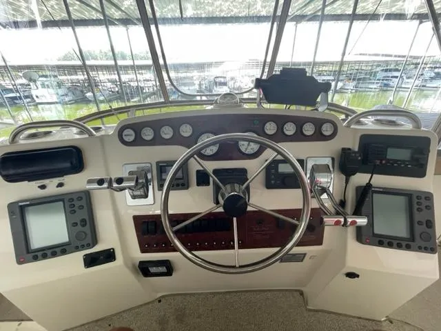 Slide: The Image of 1999 Silverton 392 Motor Yacht helm with steering wheel, gauges, and navigation equipment. - 13