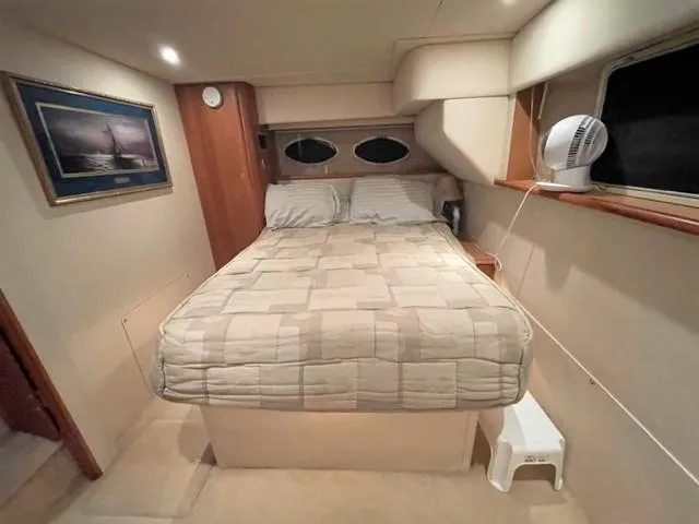 Slide: The Image of 1999 Silverton 392 Motor Yacht bedroom with double bed, wall art, and small fan. - 44