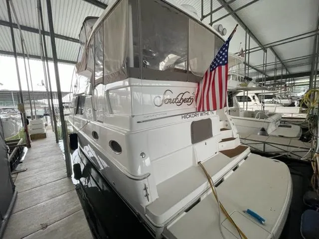 Slide: The Image of 1999 Silverton 392 Motor Yacht docked, featuring an American flag and covered upper deck. - 5