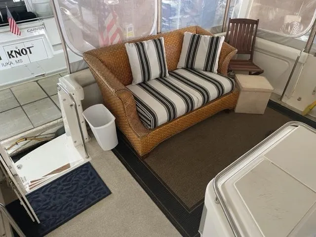Slide: The Image of 1999 Silverton 392 Motor Yacht interior with wicker sofa, striped cushions, and wooden chair. - 9