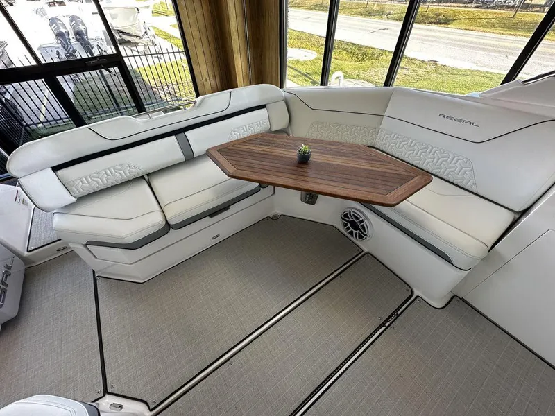 Slide: The Image of 2024 Regal LS36 boat interior with white seating and wooden table. - 27