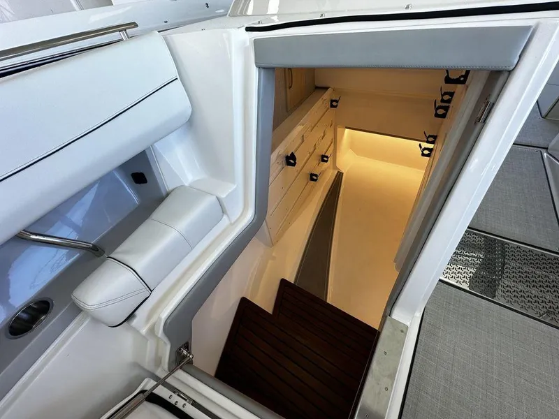 Slide: The Image of 2024 Regal LS36 boat interior cabin entrance with white seating and wooden steps. - 8