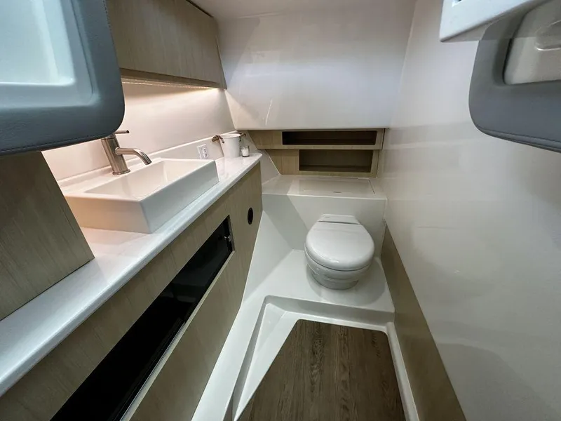 Slide: The Image of 2024 Regal LS36 boat bathroom with modern sink, toilet, and wooden cabinetry. - 9
