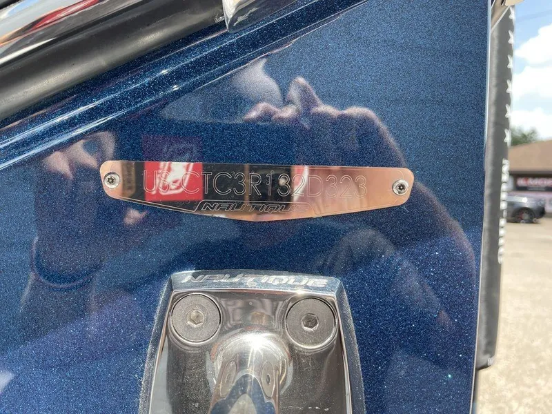 Slide: The Image of 2023 Nautique G25 Paragon boat identification plate on a metallic blue surface. - 2