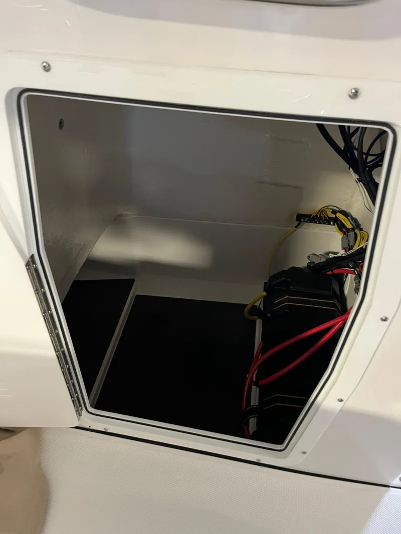 Slide: The Image of Open storage compartment in 2026 Edgewater 188CC boat, showing wiring and battery setup. - 9