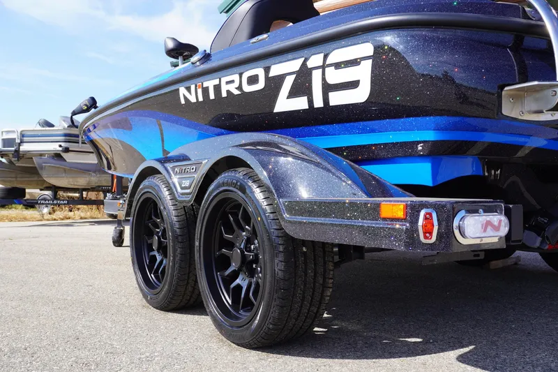 Slide: The Image of 2024 Nitro Z19 boat with sleek design and dual axle trailer on pavement. - 60