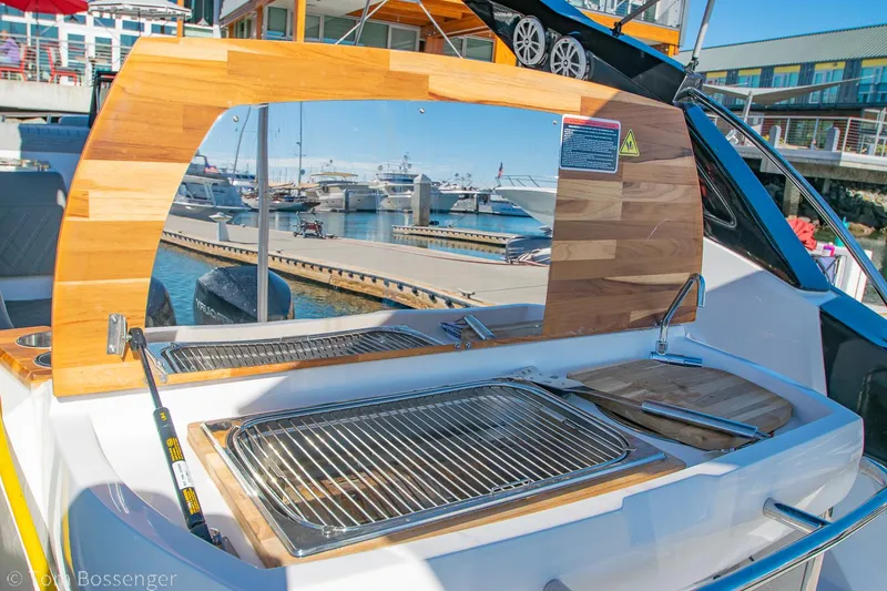 Slide: The Image of 2023 NX Boats 290 Exclusive Edition with onboard grill and marina view. - 13