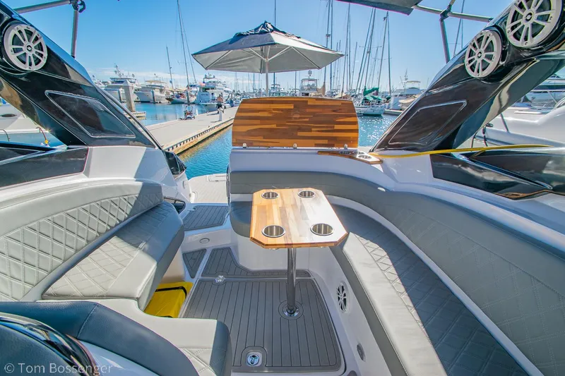Slide: The Image of 2023 NX Boats 290 Exclusive Edition interior with seating and table, docked at marina. - 16