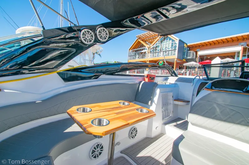 Slide: The Image of 2023 NX Boats 290 Exclusive Edition interior with seating and wooden table, docked at marina. - 17