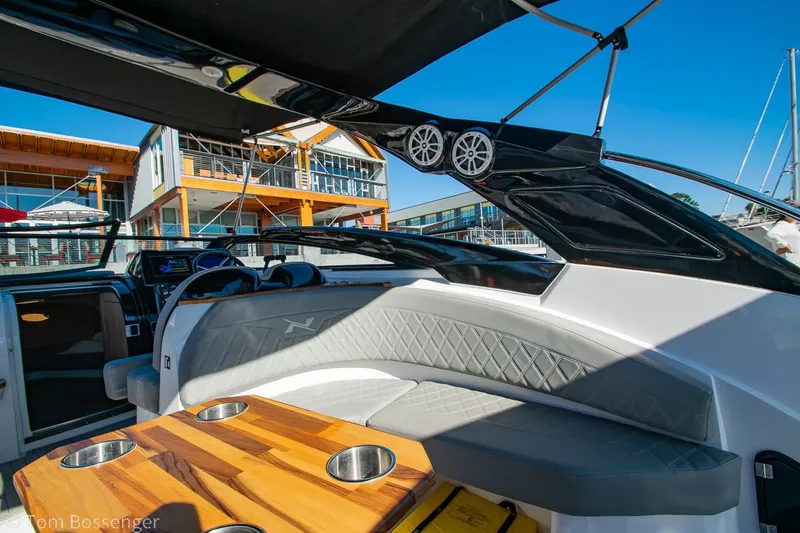 Slide: The Image of 2023 NX Boats 290 Exclusive Edition interior with luxury seating and wooden table. - 18