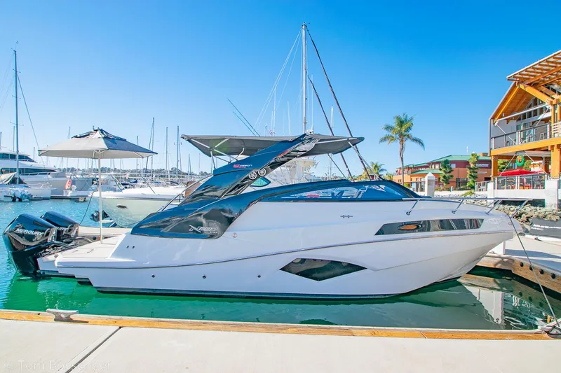 Slide: The Image of 2023 NX Boats 290 Exclusive Edition docked at a marina under clear blue skies. - 9