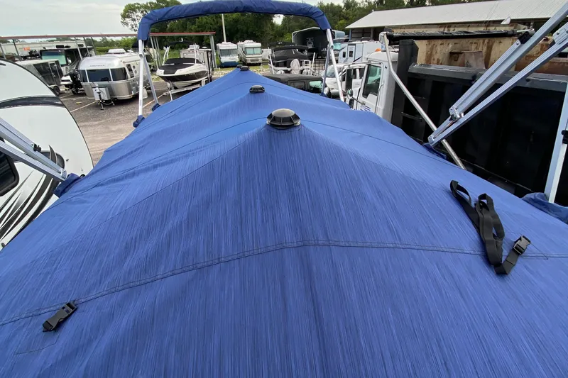 Slide: The Image of 2022 Bennington 22LSR pontoon boat with blue cover in marina. - 23