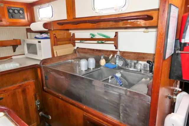 Slide: The Image of 1979 Roberts 54 boat kitchen with sink, microwave, and wooden cabinetry. - 11