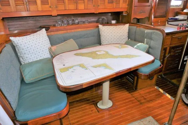 Slide: The Image of 1979 Roberts 54 yacht interior with cushioned seating and nautical map table. - 2