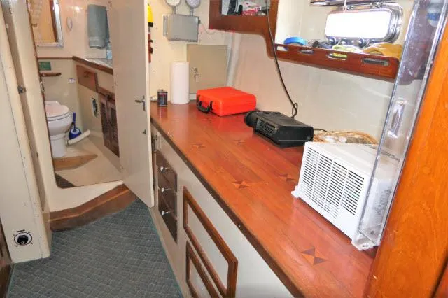 Slide: The Image of 1979 Roberts 54 boat interior with wooden countertops, storage cabinets, and a bathroom. - 23