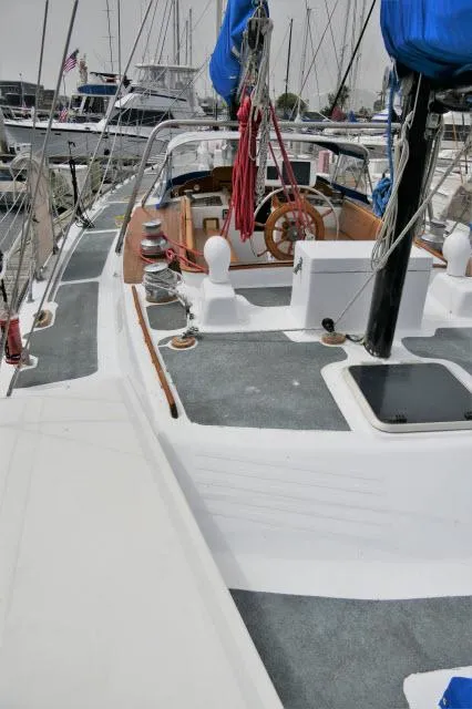 Slide: The Image of 1979 Roberts 54 sailboat docked at marina with blue sails and wooden steering wheel. - 42