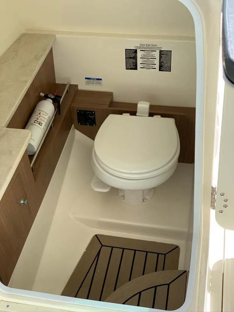 Slide: The Image of 2014 Boston Whaler 270 Vantage boat interior with toilet and storage shelves. - 11