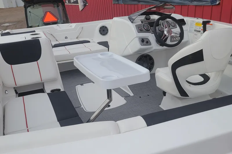 Slide: The Image of 2024 Tahoe 1950 boat interior with white and black seating, steering console, and table. - 7