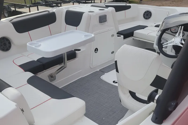 Slide: The Image of 2024 Tahoe 1950 boat interior with white and black seating, table, and steering wheel. - 8