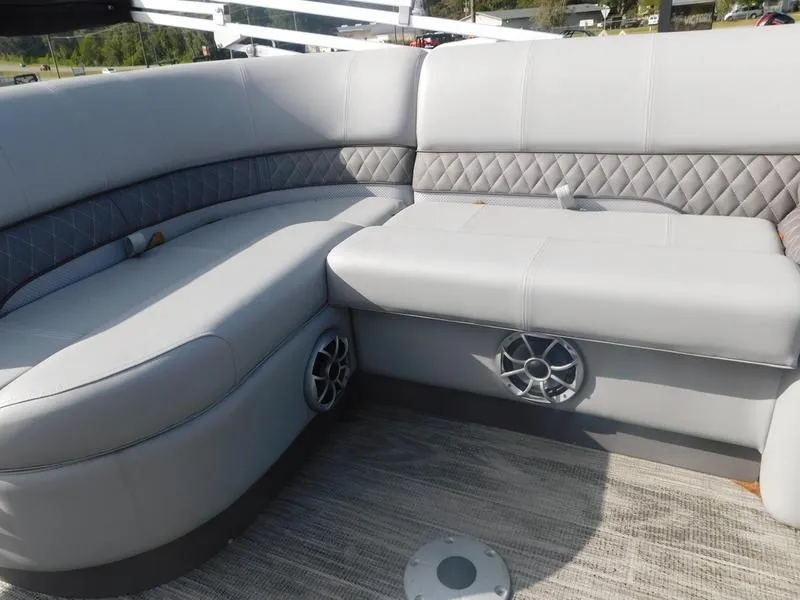 Slide: The Image of 2024 Ranger Reata 223FC boat interior with gray cushioned seating and built-in speakers. - 10