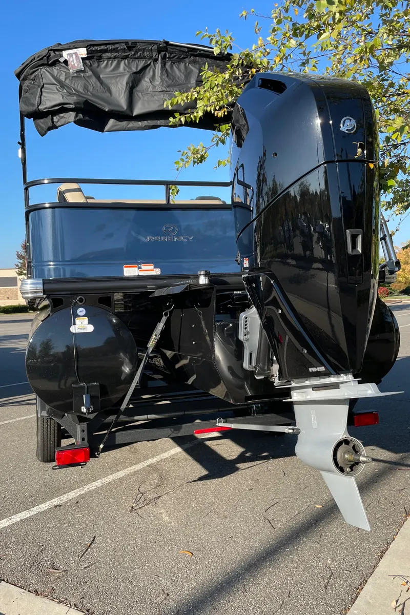 Slide: The Image of 2024 Regency 250 DL3 pontoon boat with outboard motor, rear view. - 6
